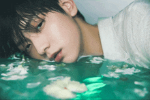 a man in a white shirt is laying in a pool of water