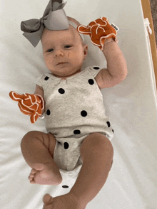 a baby wearing a polka dot bodysuit is laying on a blanket