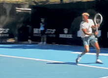 a man is playing tennis on a blue court with a sign behind him that says ' a ' on it