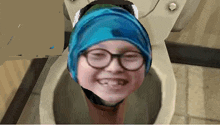 a child wearing glasses and a blue hat is sitting in a toilet