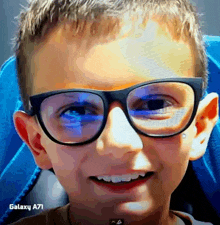 a young boy wearing glasses and a galaxy a71 behind him