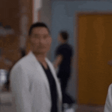 a man in a white coat is standing in a hallway in a hospital .