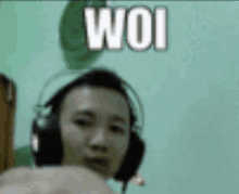 a man wearing headphones is giving a fist bump in front of a wall that says woi .