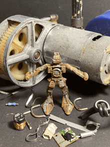 a rusty toy robot is standing next to a gear