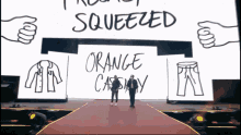 two people standing in front of a large screen that says squeezed