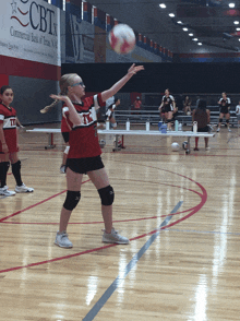 a girl playing volleyball in front of a banner that says cbtx