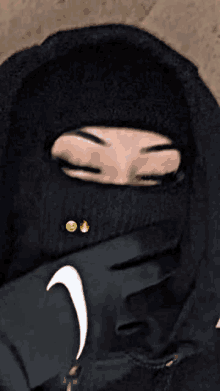 a woman is wearing a ski mask and a hoodie .