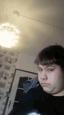 a man in a black sweater with the letter t on it looks at the camera