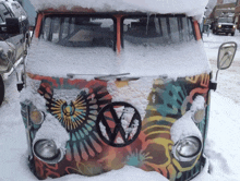 a volkswagen van is covered in snow with a colorful design on the front