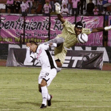 two soccer players are playing a game on a field with a banner in the background that says sentimento rio