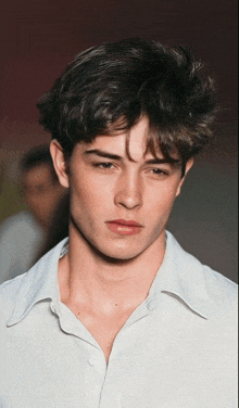 a close up of a young man 's face with a white shirt