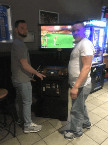 two men are standing in front of a bud light machine