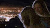 two women are hugging in front of a city at night