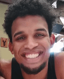 a close up of a man with curly hair and a beard smiling .