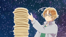 a man with glasses holds a stack of pancakes in his hand