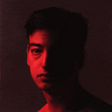 a close up of a man 's face with a red light behind him