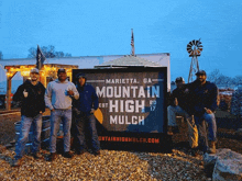 a group of men are posing in front of a sign that says mountain high mulch