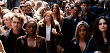 a crowd of people walking down a street including a woman with red hair