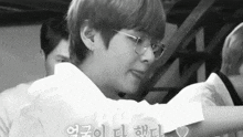 a black and white photo of a person wearing glasses and a white shirt .