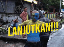 a man with blue and yellow paint on his face stands in front of a sign that says " lanjutkan "