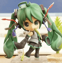 a figurine of a girl with green hair and headphones is sitting on a table