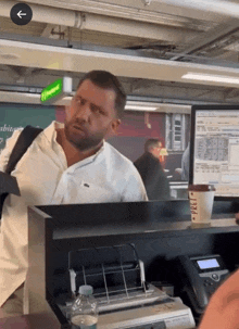 a man in a white shirt stands in front of a starbucks counter