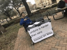 a man is sitting at a table with a sign on it that says `` undyne is harder than sans '' .