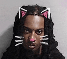 a man with dreadlocks and cat ears on his head is looking at the camera .