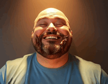 a man with a beard and a blue shirt is smiling with his eyes closed