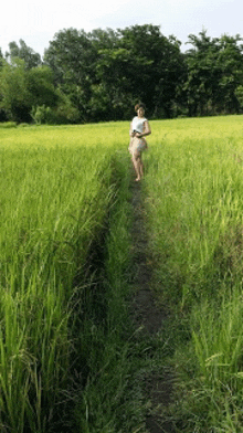 a woman is walking through a grassy field .