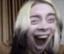 billie eilish is making a funny face with her mouth open in a blurry photo .