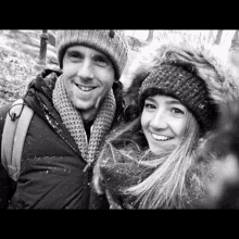 a black and white photo of a man and a woman wearing hats and scarves