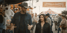 a man in a cowboy hat talks to a woman in front of a sign that says annual ranger community fair