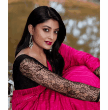 a woman wearing a black lace blouse and a pink saree