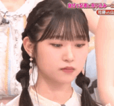 a close up of a girl 's face with pigtails and earrings .