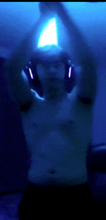 a man without a shirt is wearing headphones in a blue room