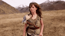 a woman is standing in a field with a gun in her hand