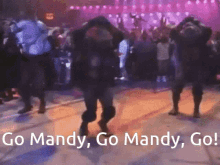 a group of people are dancing with the words go mandy go mandy go in the background