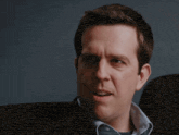 a close up of a man 's face with a blue shirt on