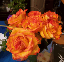 a bunch of orange and yellow roses on a blue table