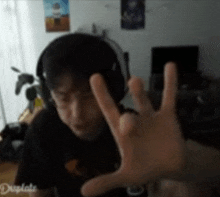 a man wearing headphones is making a peace sign with his hand