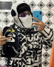 a man wearing a mask and sunglasses is taking a selfie in a mirror .