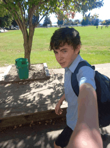 a young boy with a backpack takes a picture of himself