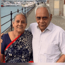 a man and woman are posing for a picture in front of a harbor