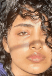 a close up of a woman 's face with curly hair looking at the camera