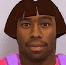 a man wearing a dora the explorer wig and a purple shirt is looking at the camera .