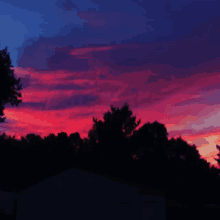 a sunset with trees in the foreground and a purple sky in the background