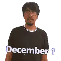 a man wearing glasses and a black shirt is pointing up at the date december 1