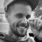 a man with a beard wearing a hat is smiling for the camera