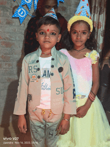 a boy and a girl are posing for a picture taken by a vivo v27 phone